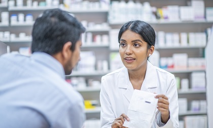 A pharmacist handing a prescription to a patient