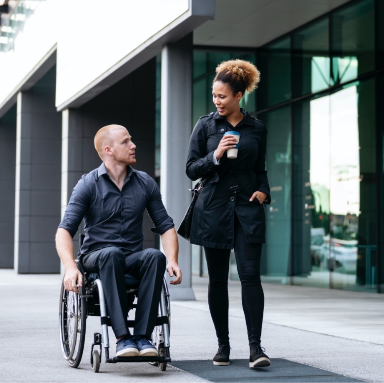 young Canadian woman with a man in a wheelchair enjoying a stroll together