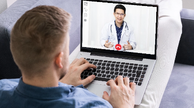 Man using a laptop showing a doctor on the screen