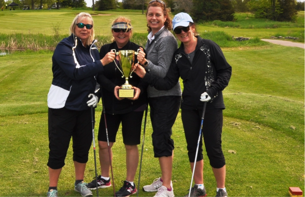 Four Empire Life employees hold a trophy at a charity golf tournament