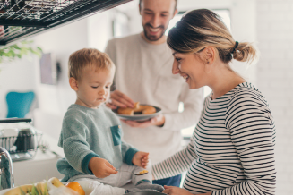 Young couple with toddler cooking breakfast together